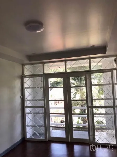 Townhouse for rent in Suan Luang, Bangkok - Room with French doors and security grilles overlooking greenery.