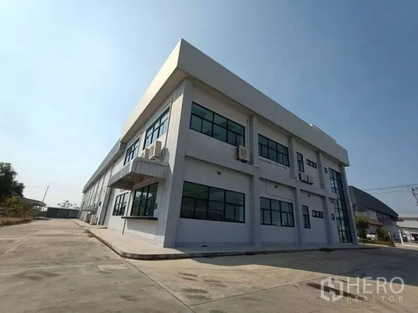 Warehouse for rent or sale in Pathum Thani - Modern two-storey warehouse exterior with wide driveway in Khlong Luang, Pathum Thani.