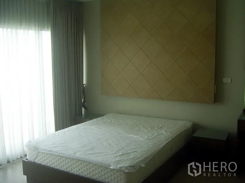 Condominium for rent in Khlong Toei, Bangkok - Bright master bedroom with large window, sheer curtains and feature headboard wall panel.