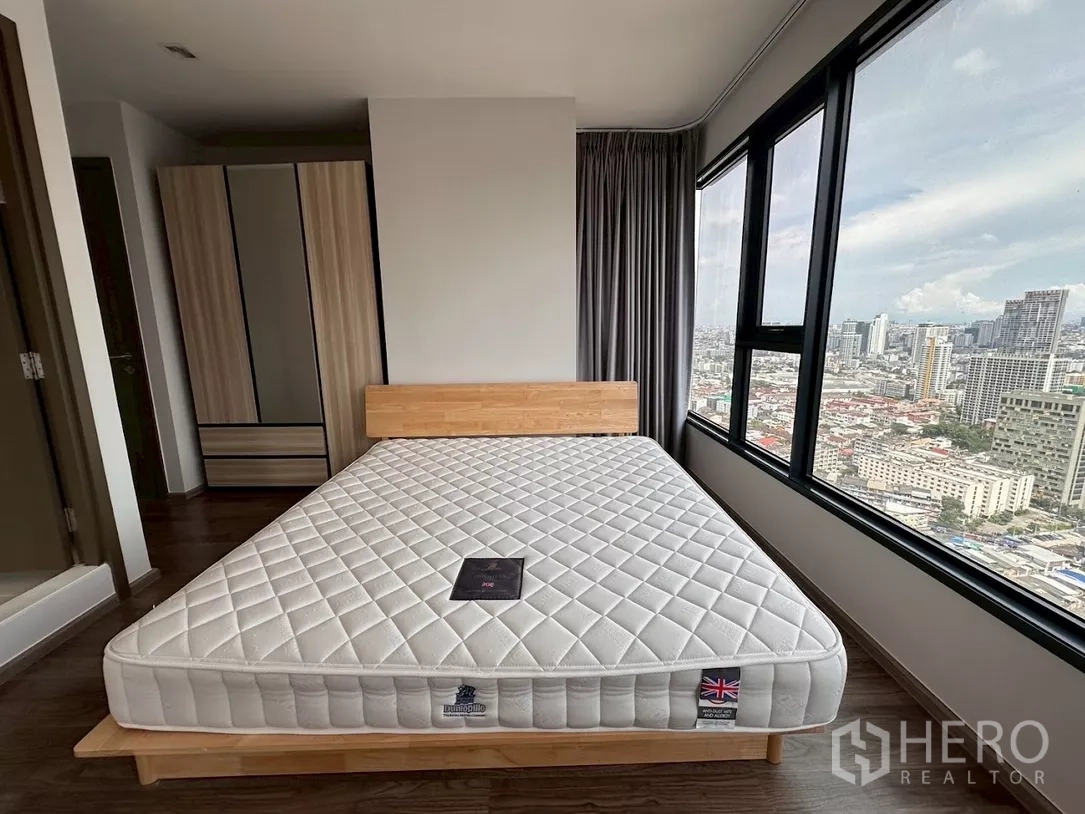 公寓 出租在Chatuchak, Bangkok - 卧室设城市景观大窗、木床架与衣柜。