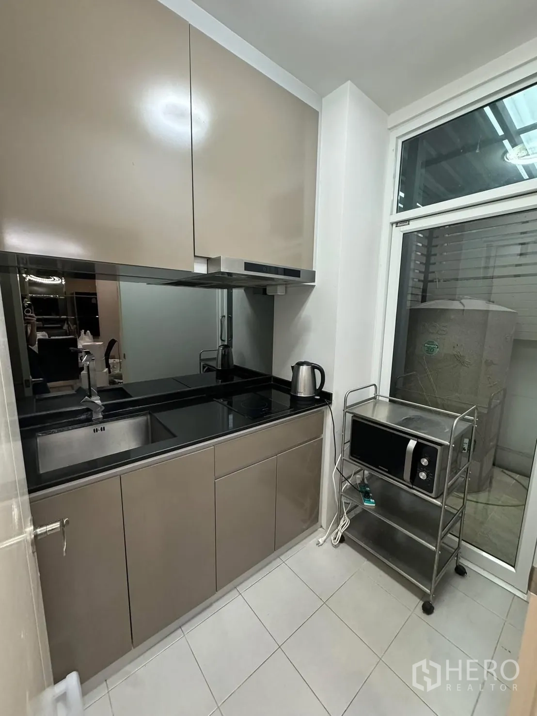 Townhouse for rent in Suan Luang, Bangkok - Compact modern kitchen with glossy cabinets, black countertop and window to utility area.