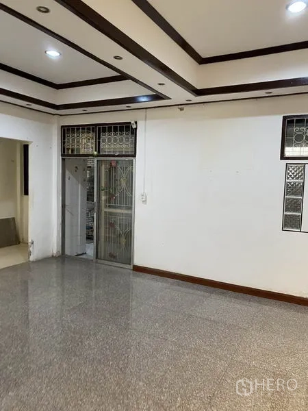Townhouse for rent in Lat Phrao, Bangkok - Spacious room with recessed ceiling lights and a sliding metal door.