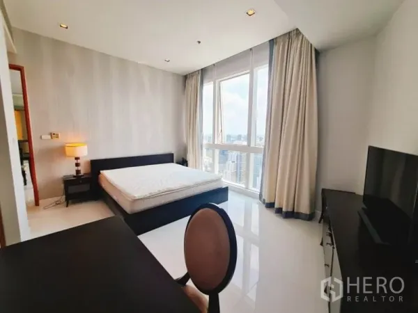 Condominium for rent in Khlong Toei, Bangkok - Bedroom with large windows, city skyline view, TV console and work desk.