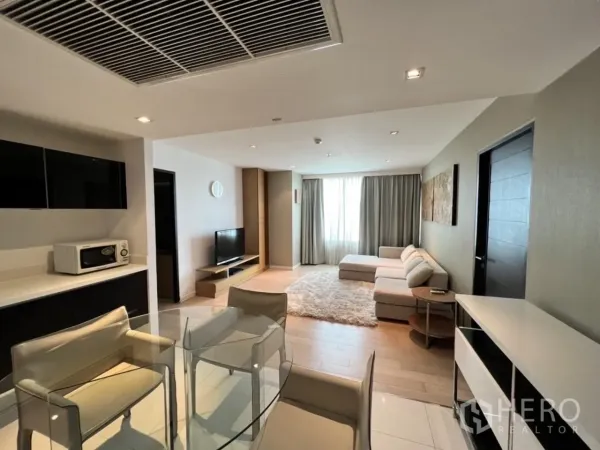 Condominium for rent in Watthana, Bangkok - Bright open-plan living room with L-shaped sofa, TV console and large window in a Thonglor condo.