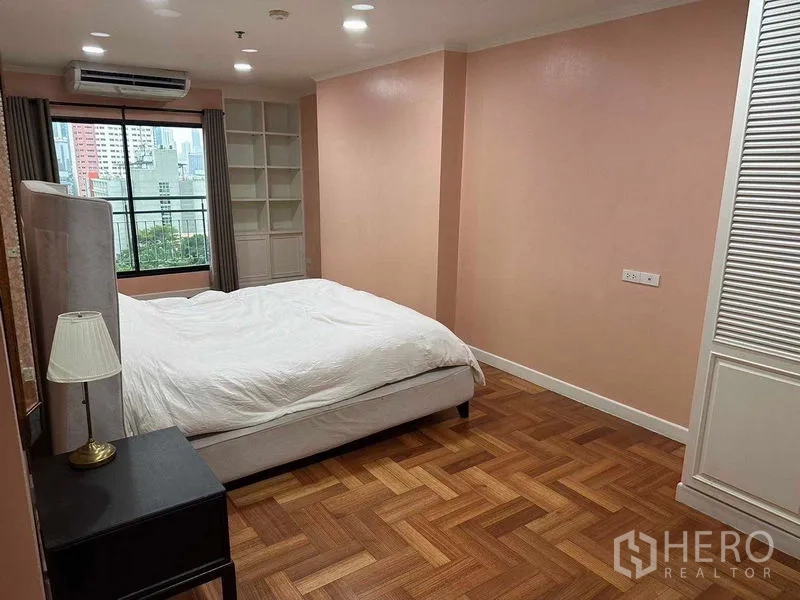 公寓 出租或出售在Bangkok - 主卧朝向大窗，内置书架并享城市天际线景观。