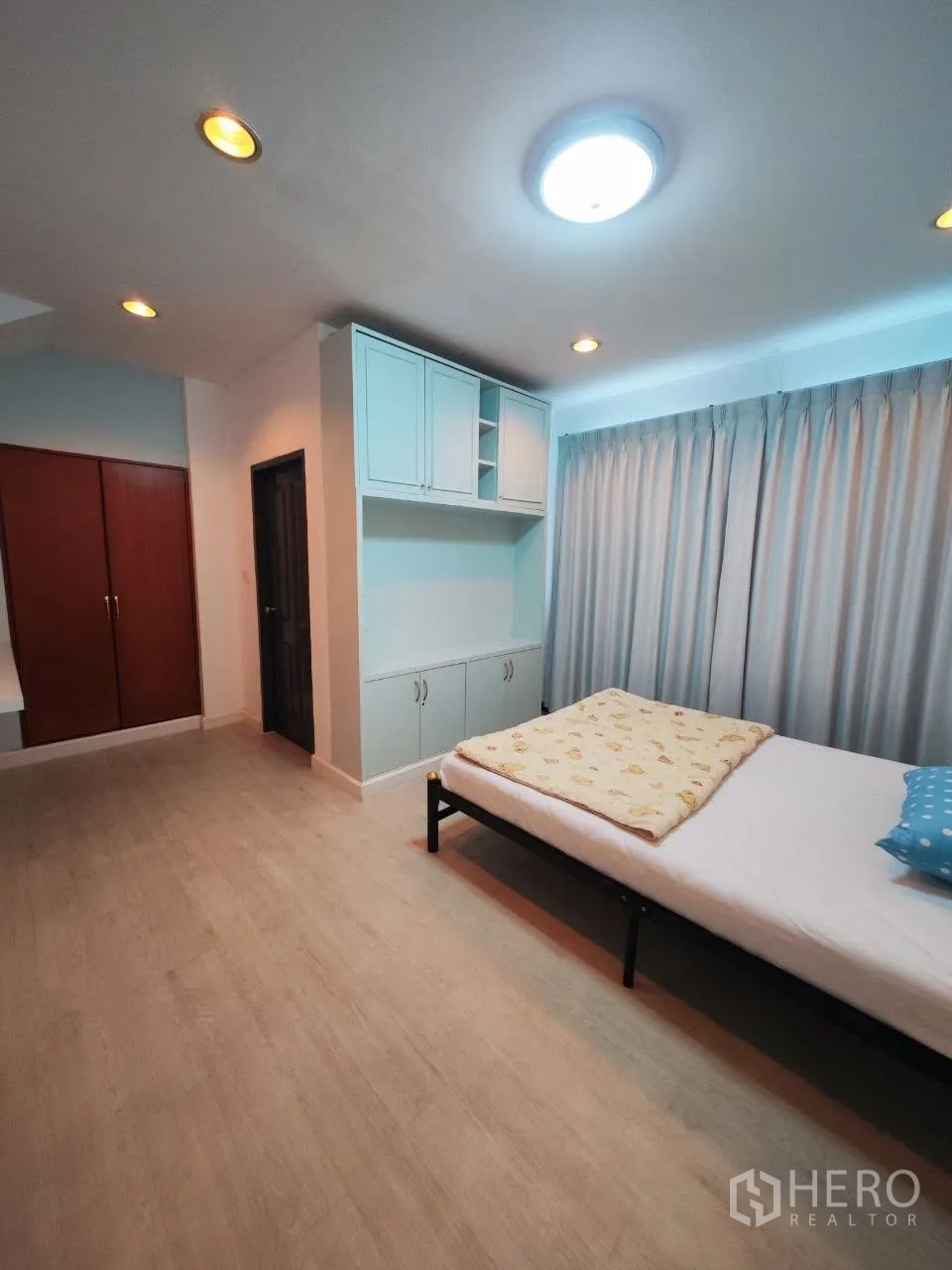 Home Office for rent in Bang Na, Bangkok - Bedroom with bed, built-in cabinets and warm lighting.