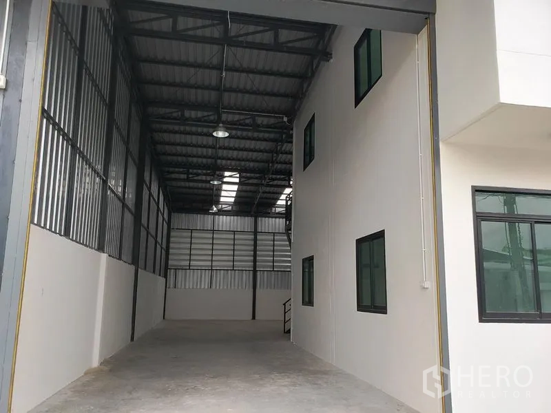 Warehouse for rent or sale in Lam Luk Ka, Pathum Thani - Wide covered loading bay leading into the warehouse, adjacent to the office facade and high roof lights.