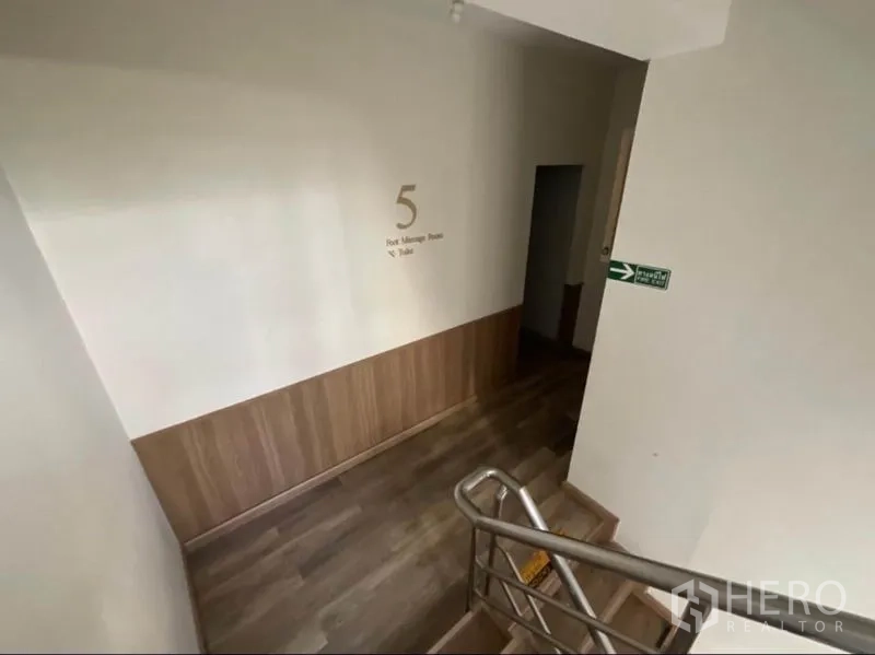 Shophouse for rent in Khlong Toei, Bangkok - Stairwell landing with wood flooring and wall signage directing to foot massage rooms.