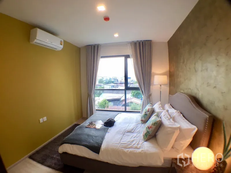Condominium for rent in Khlong Toei, Bangkok - Master bedroom angle showing big window over low-rise views, gray headboard and gold accent wall.