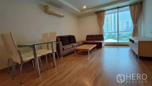 Condominium for rent in Khlong Toei, Bangkok - Bright living room with floor-to-ceiling windows, city view, sofa set and glass dining table on warm wood floors.