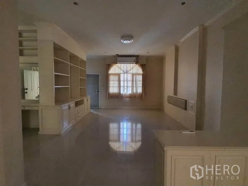 Townhouse for rent in Huai Khwang, Bangkok - Spacious family room with built-in shelving, window and glossy tile flooring.
