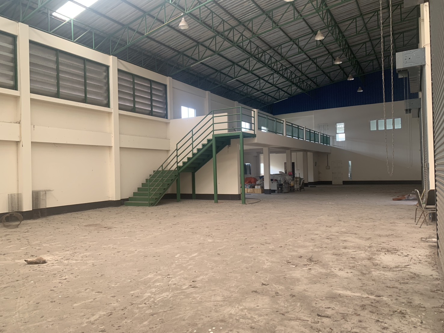 Warehouse for rent in Lam Luk Ka, Pathum Thani - Wide view of the warehouse showing a green staircase up to the mezzanine level.