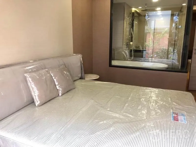 公寓 出租在Pathum Wan, Bangkok - 卧室配大床，透过玻璃可见带浴缸与淋浴的浴室。