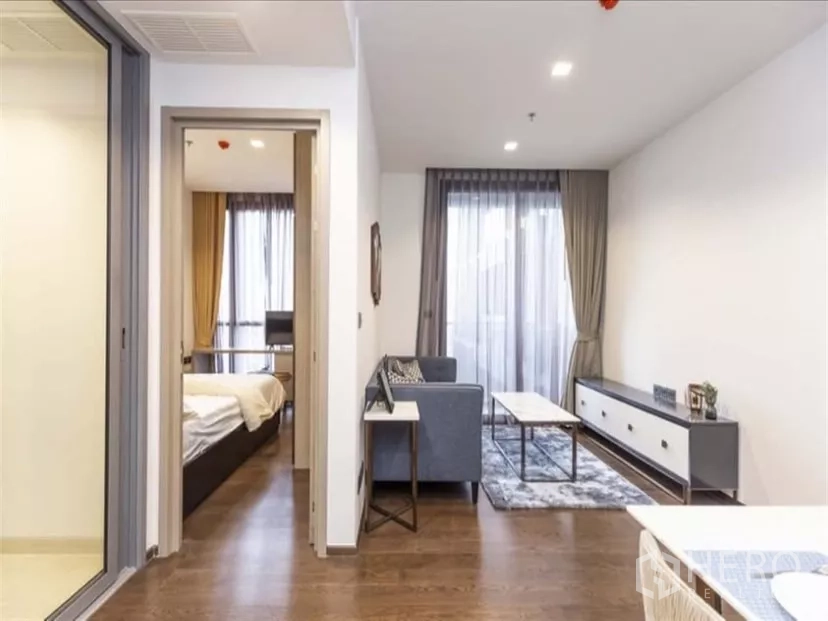 公寓 出租在Ratchathewi, Bangkok - 从走廊望向起居区，电视柜与地毯，落地窗阳台，左侧为卧室门口。