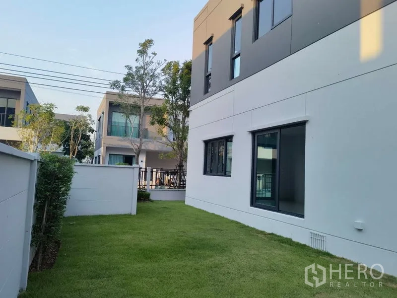 Detached House for rent in Bang Phli, Samut Prakan - Side yard with grass lawn beside a contemporary two-storey facade.