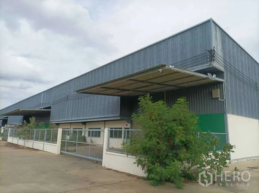 工厂 for rent in Ban Phaeo, Samut Sakhon - 大型钢结构厂房外观，带遮雨装卸棚、围栏与宽阔混凝土车道。