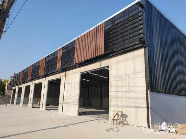 货栈 出租在Nonthaburi - 帕克雷现代仓库外立面，设有多组大型装卸门与通风立面板。