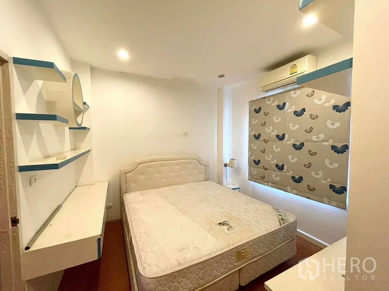 Townhouse for rent in Saphan Sung, Bangkok - Cozy bedroom with upholstered headboard, built‑in shelves, work desk and air conditioning.