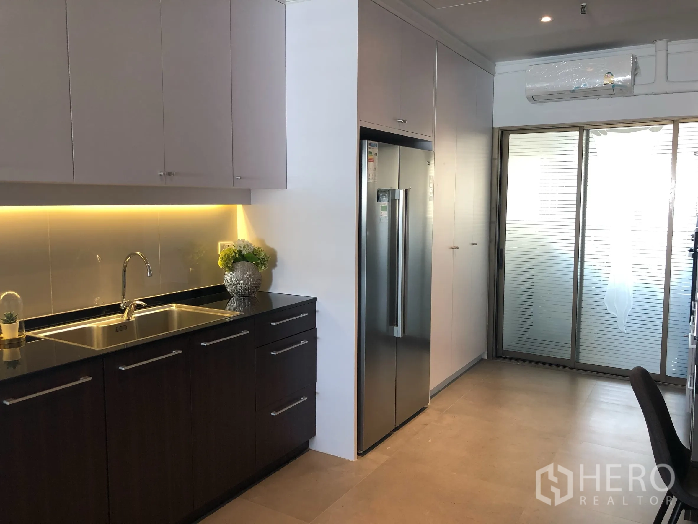 Condominium for rent in Bangkok - Modern enclosed kitchen with under-cabinet lighting and stainless refrigerator.