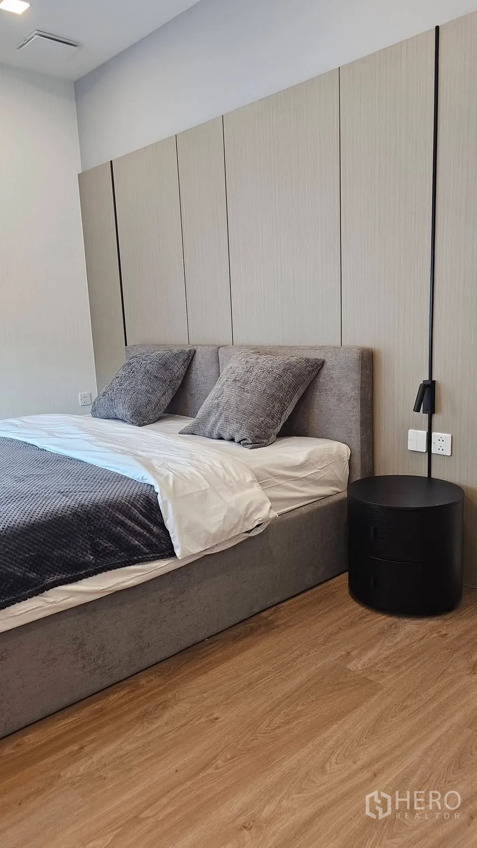 独栋房屋 for rent in Bang Phli, Samut Prakan - 温馨卧室，软包床、木地板与黑色圆形床头柜。