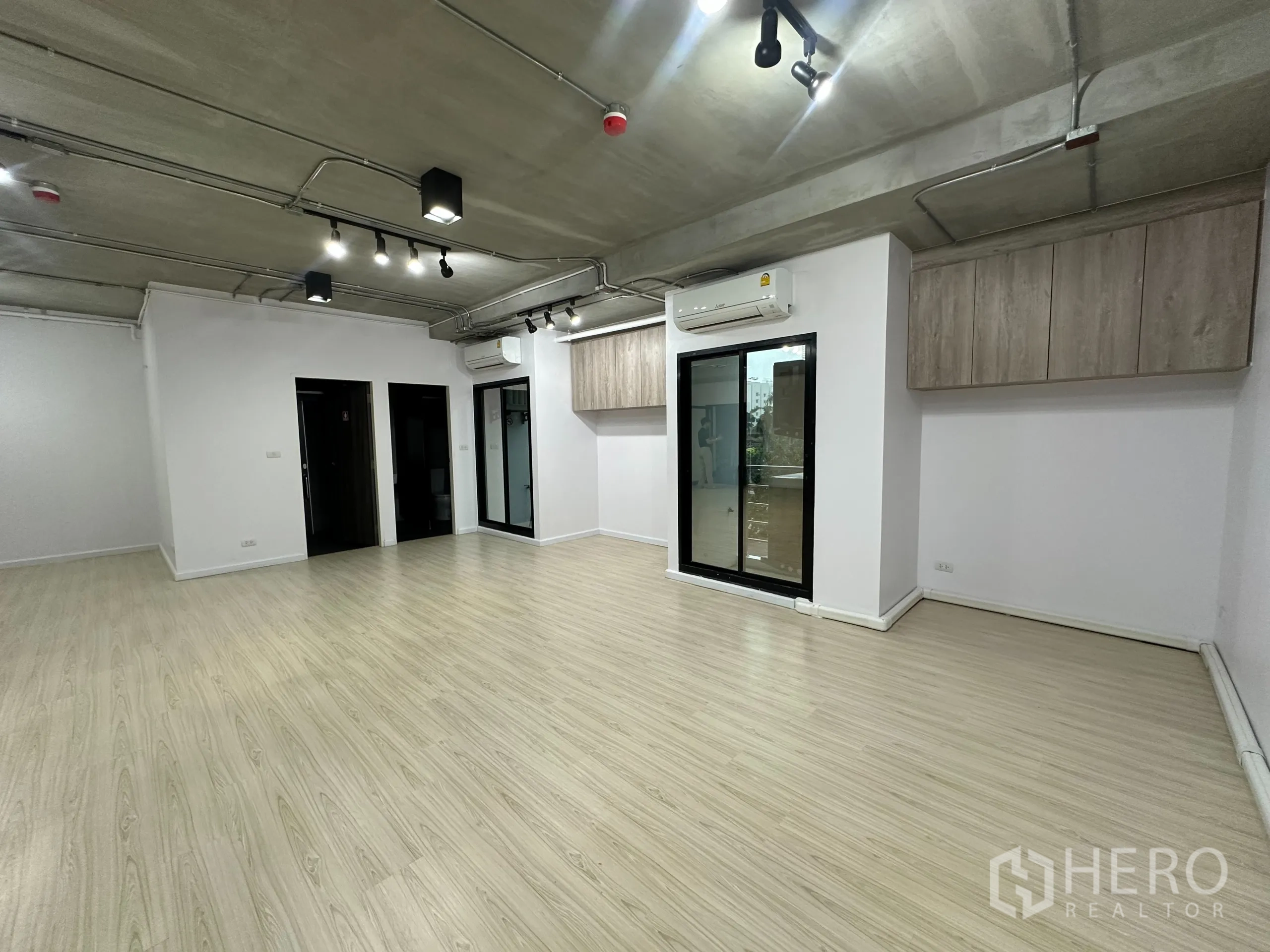 办公空间 出租在Watthana, Bangkok - 办公室一角，滑动玻璃门、壁挂柜与分体式空调。