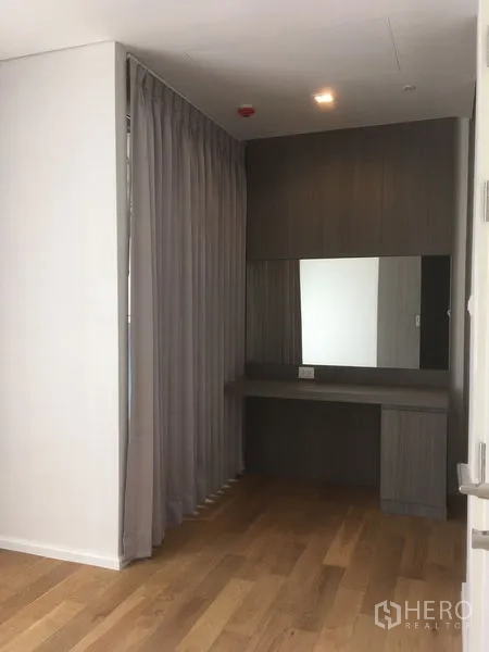 Condominium for rent or sale in Chatuchak, Bangkok - Built-in dressing corner with desk, large mirror and grey cabinetry behind a curtain.