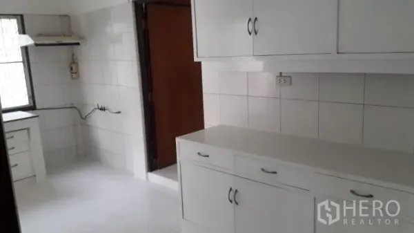 Detached House for rent in Yan Nawa, Bangkok - Bright white-tiled kitchen with upper and lower cabinets and a window.