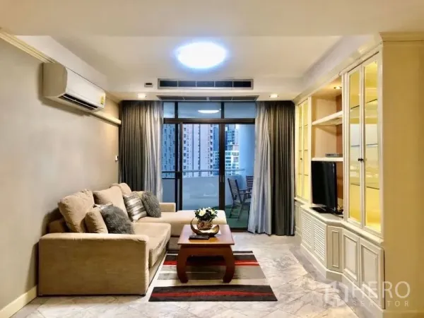 Condominium for rent in Watthana, Bangkok - Bright living room with sofa, media built-ins and sliding doors to a city-view balcony