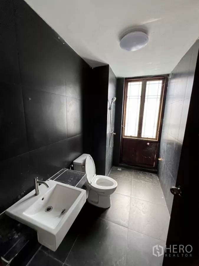 Retail Space for rent in Khlong Toei, Bangkok - Modern black-tiled bathroom with shower, sink and toilet.