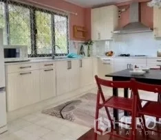 Detached House for rent in Phra Khanong, Bangkok - Modern family kitchen with white cabinetry, large window, range hood and dining set.
