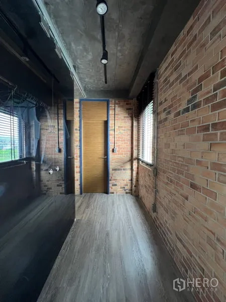 Townhouse for rent in Saphan Sung, Bangkok - Industrial hallway with exposed brick walls, track lights, and dark glass wardrobe.