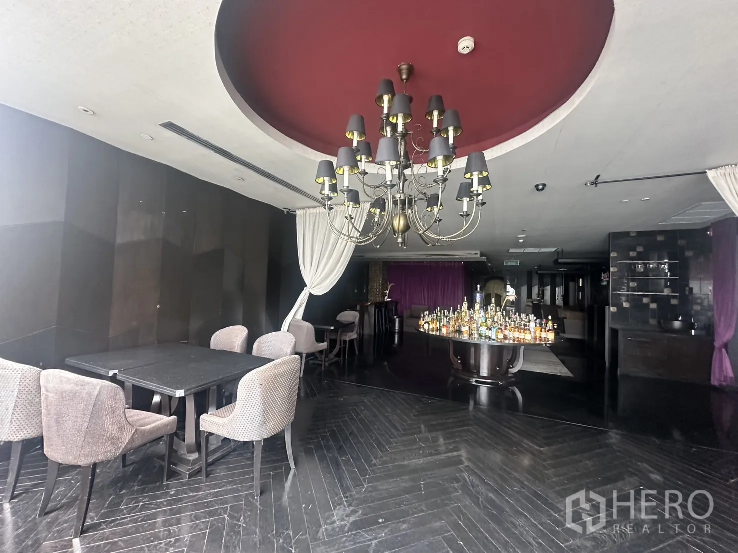 Retail Space for rent in Khlong Toei, Bangkok - Dining corner with chandelier, draped curtains and tables around a bottle display.