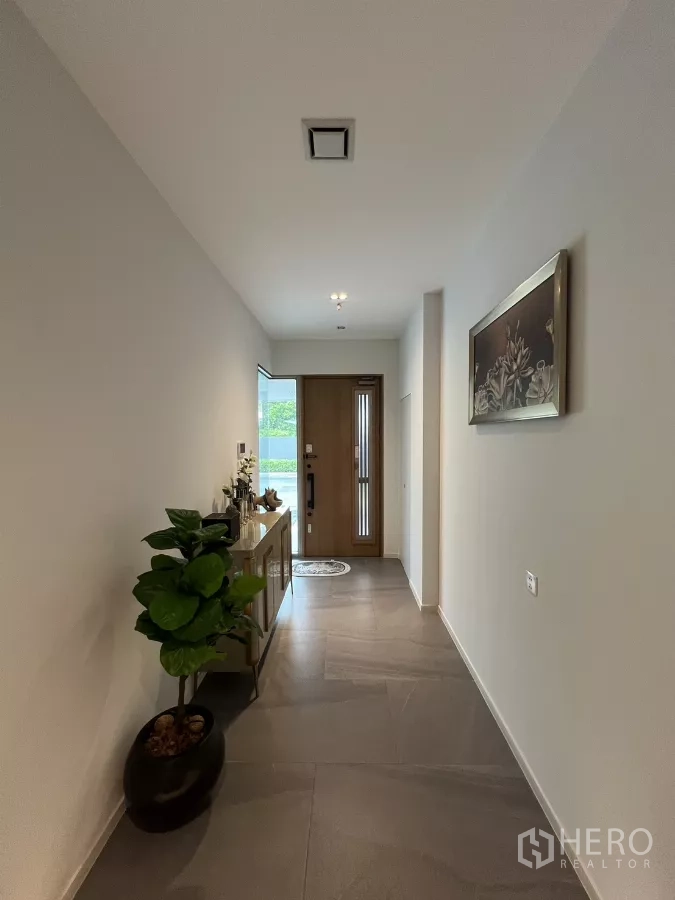 Detached House for rent in Saphan Sung, Bangkok - Bright entry corridor with large floor tiles, a wooden door and console table.