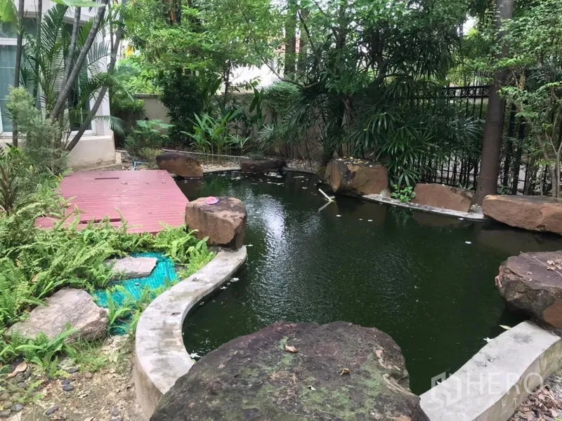 独立式住宅 出租在Bang Khen, Bangkok - 花园内的景观鱼池，点缀巨石与茂密树木。