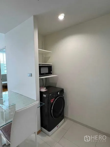 Condominium for rent in Ratchathewi, Bangkok - Laundry corner with front-load washing machine and microwave shelves.