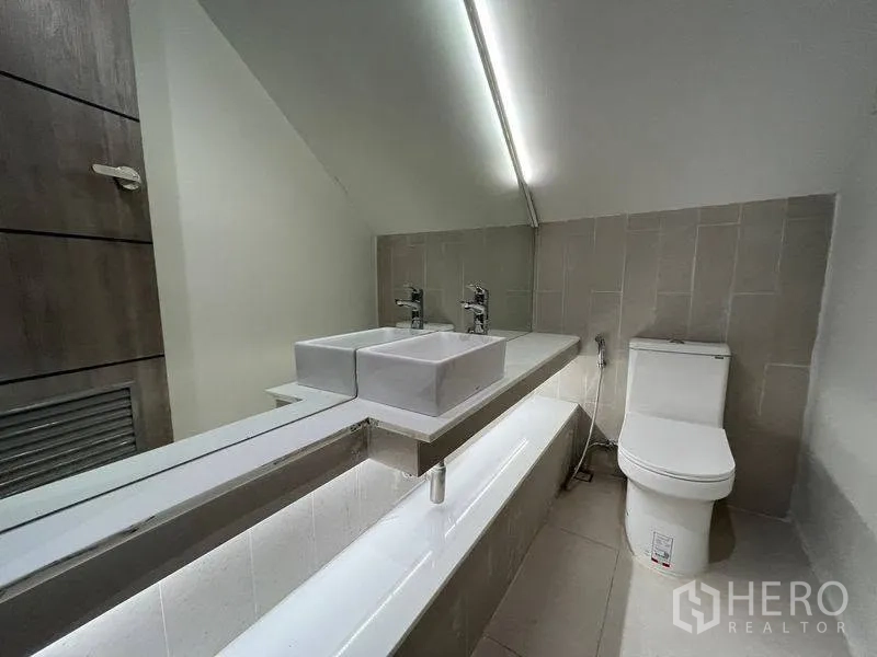 ทาวน์เฮาส์ for rent in Phra Khanong, Bangkok - ห้องน้ำมีอ่างล้างหน้าคู่ กระจกยาว และโถสุขภัณฑ์ใต้ฝ้าลาดเอียง.