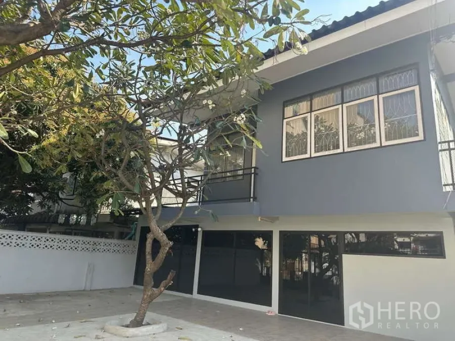 Home Office for rent in Din Daeng, Bangkok - Street-facing exterior of a modern two-storey home office with balcony and frangipani tree.