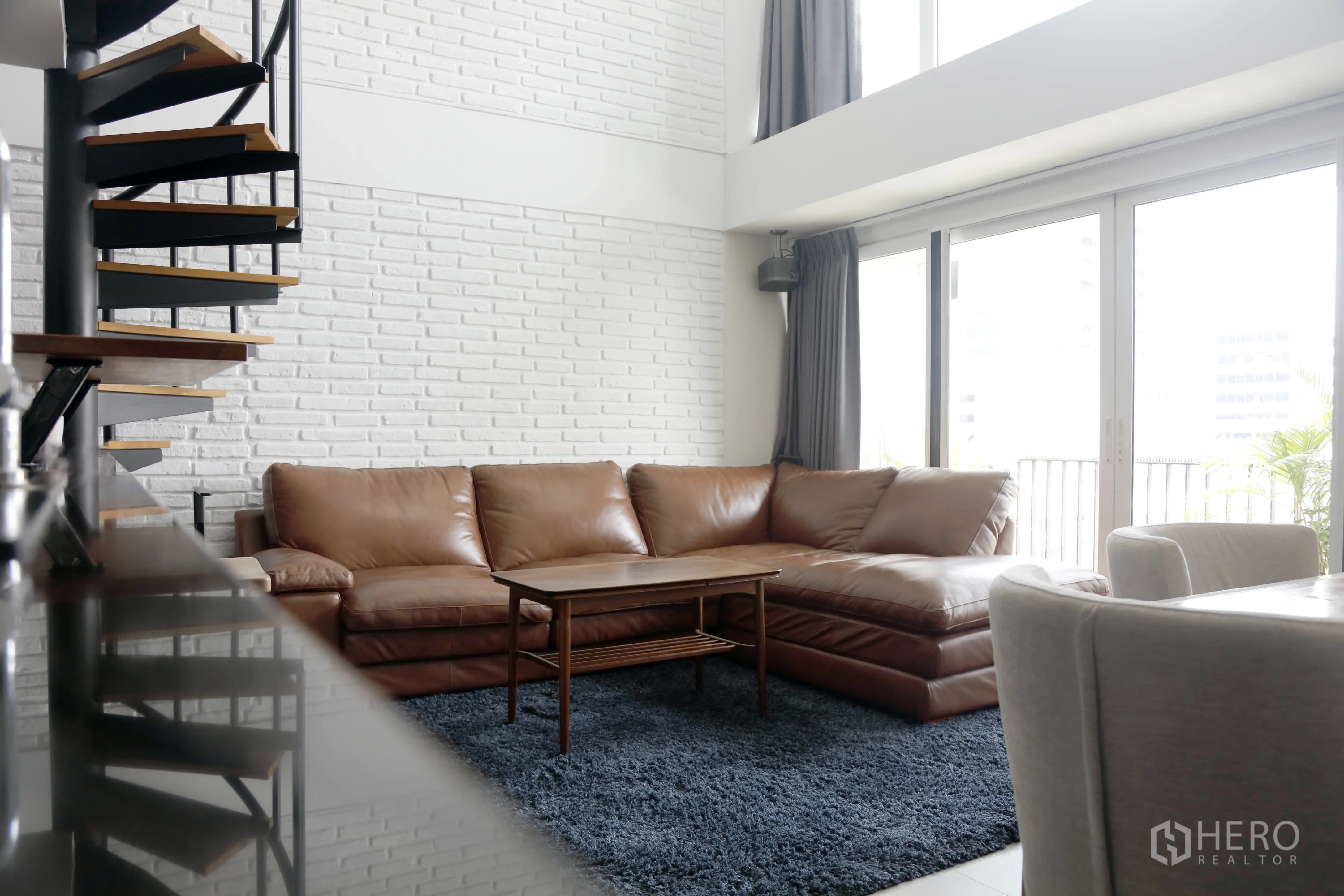 คอนโด for rent in Watthana, Bangkok - ห้องนั่งเล่นมีโซฟาหนังสีน้ำตาลรูปตัวแอลและประตูบานเลื่อนกระจก