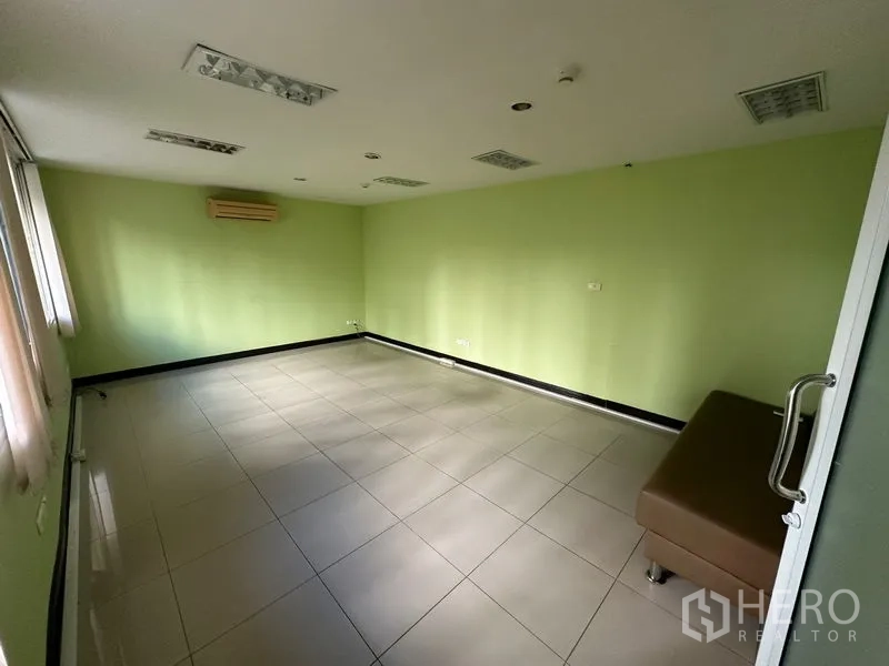 Office Space for sale - Empty square office with green walls, tiled floor and wall-mounted air conditioner.