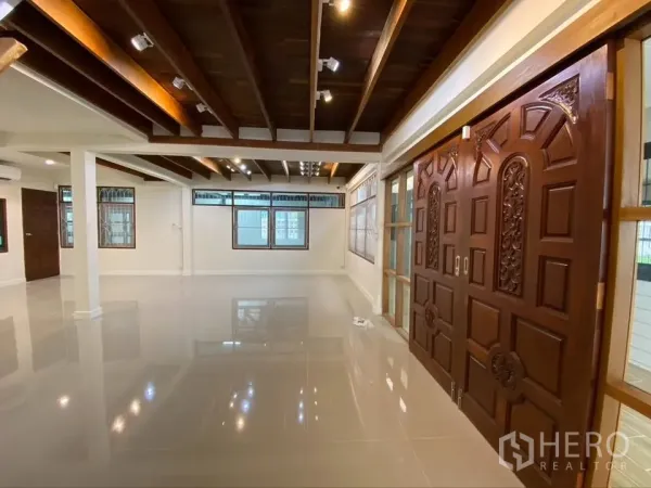 Detached House for rent in Suan Luang, Bangkok - Open-plan living area with glossy floors, beamed ceiling, and carved doors.