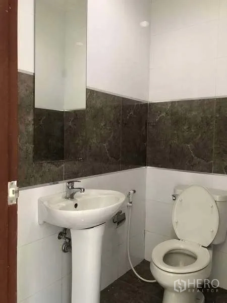 工厂 出租或出售在Bang Phli, Samut Prakan - 整洁的瓷砖卫生间，配立柱式洗手盆、镜子与坐便器。