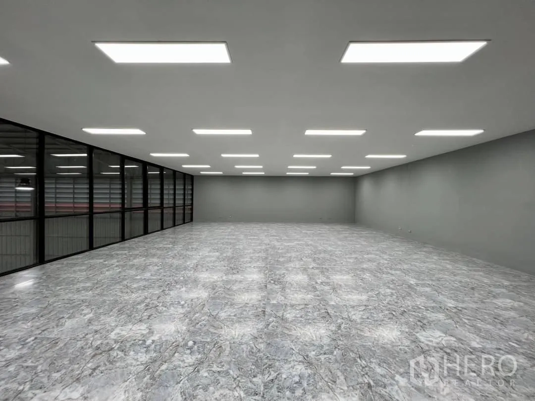 Warehouse for rent in Sai Mai, Bangkok - Open-plan mezzanine office with LED panels and a full-length glass wall over the warehouse.