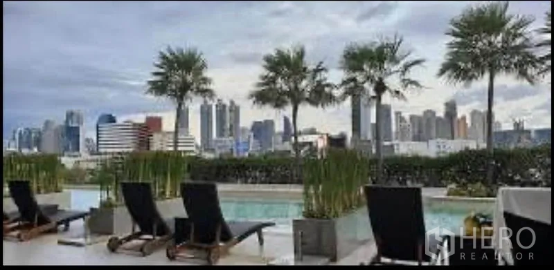 Condominium for rent in Sathon, Bangkok - Rooftop swimming pool with sun loungers and palm trees overlooking the Bangkok skyline.
