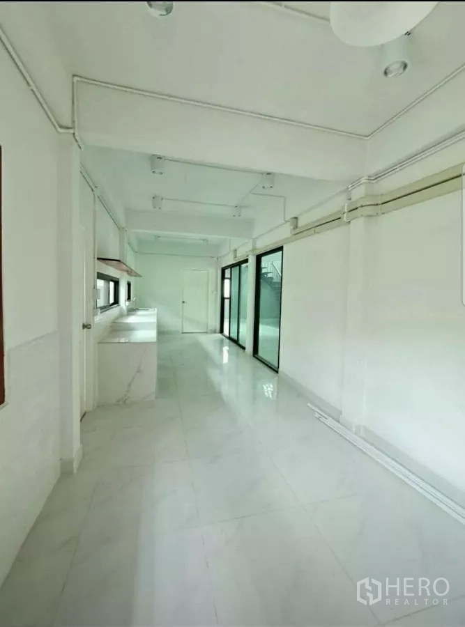 带办公室的家 出租在Lat Phrao, Bangkok - 狭长一字型茶水厨房，白色台面，推拉门通往庭院。