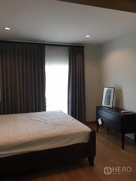 Detached House for rent in Suan Luang, Bangkok - Master bedroom with large bed, wood flooring and blackout curtains.