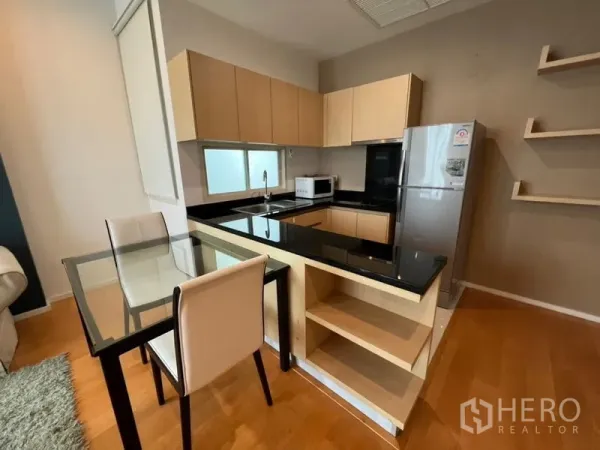 Condominium for rent in Chatuchak, Bangkok - Modern U-shaped kitchen with black granite counters, light wood cabinets and dining set