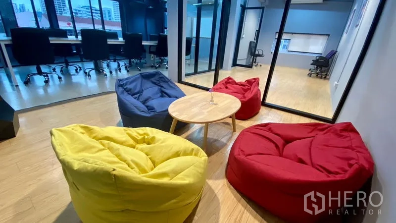 สำนักงาน ให้เช่าในSathon, Bangkok - โซนพักผ่อนบีนแบ็กสีสันสดใสกับโต๊ะกลม ข้างห้องทำงานกั้นกระจกในออฟฟิศสมัยใหม่