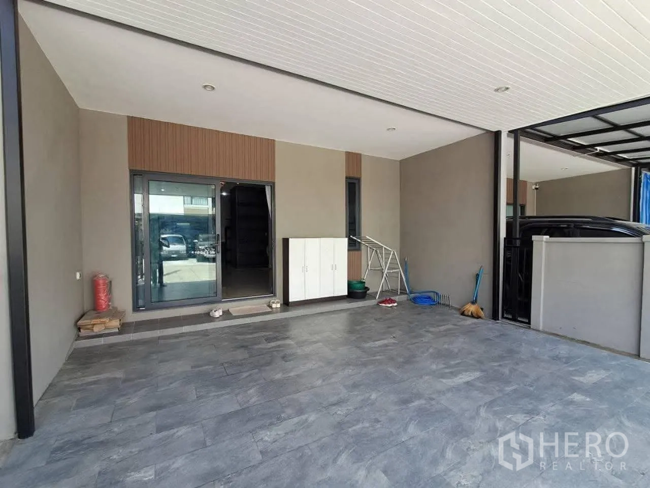 Townhouse for rent in Bang Kapi, Bangkok - Covered carport with tiled floor, sliding glass entry and storage cabinet.