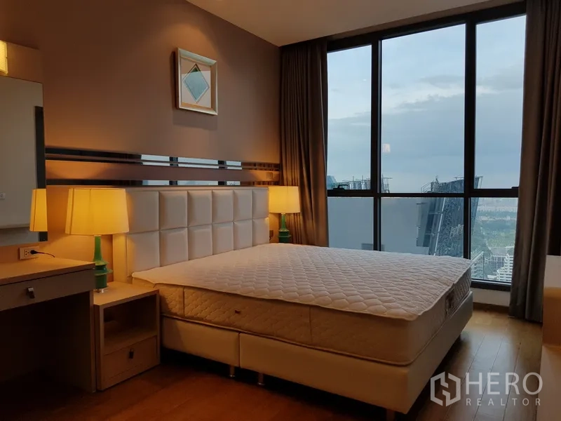 Condominium for rent in Watthana, Bangkok - Second bedroom with bedside lamps and tall windows overlooking city