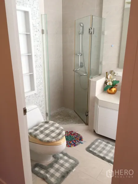 Condominium for rent in Khlong Toei, Bangkok - Modern ensuite bathroom with glass shower, white vanity and toilet.